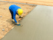 A worker adjusts levels of concrete in formwork using a trowel. For smoothing and polishing concrete slab.