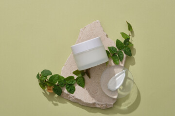 Sticker - A broken stone podium with blank label jar, green leaves and a transparent podium in round shape with cream texture displayed on. Skin care concept