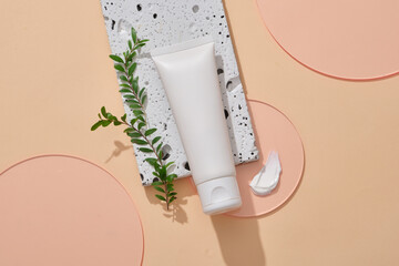 Wall Mural - An empty label cosmetic tube put on stone podium, decorated with leaves, cream texture and few pink acrylic sheets. Beauty branding product mockup