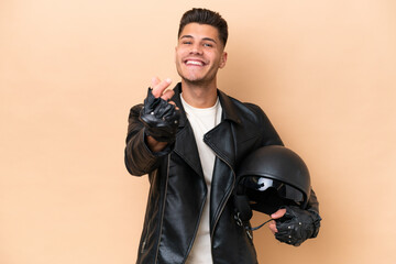 Wall Mural - Young caucasian man with a motorcycle helmet isolated on beige background making money gesture