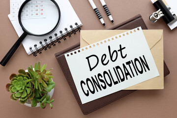 debt consolidation, Office desk with text on a notebook. magnifying glass, pen, glasses, calendar and a small plant on a brown background