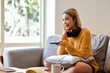 .Photo of fashion asian woman holding remote control and watching TV, while sitting at sofa in cozy apartment.