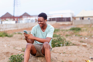 Wall Mural - happy young male model sitting using mobile phone for sending and receiving mails