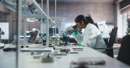 Fototapete - Young Indian Science Student Conducting Electronics Experiment in a University Workshop. Diverse Young Scholar Using Microscope, Working on Connecting a Circuit Board