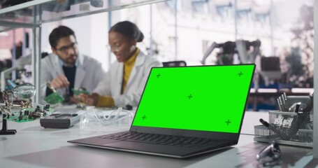 Fototapete - Laptop Computer with Green Screen Mock Up Display Standing on a Table in a Science Class Laboratory. Young African Female Student Having a Conversation with a Teacher About Her Electronics Project