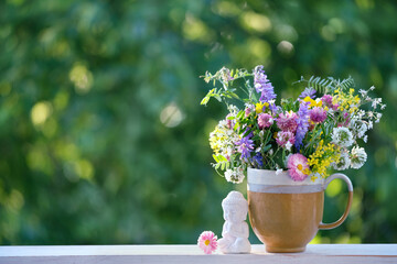 Wall Mural - Buddha statue and meadow flowers in cup on table, abstract green natural background. spring, summer season. esoteric spiritual practice for harmony, meditation. Relax time. life balance concept