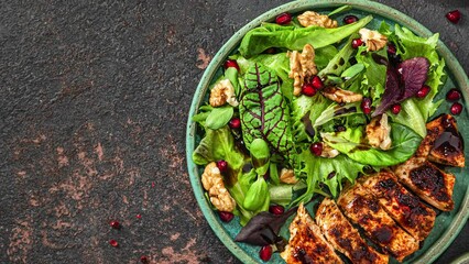 Poster - Salad with grilled chicken fillet, mix greens, walnuts, pomegranate and balsamic sauce on black background. top view with copy space. healthy diet food