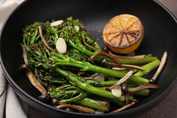 Wall Mural - Tasty cooked broccolini with lemon and mushrooms in bowl, closeup