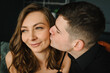 © Serhii - Couple in love closeup at home. Handsome boyfriend kiss beautiful girlfriend. Smiling family relaxing, resting on sofa. Holiday, leisure time in living room. Man and woman laughing, hugging in house.