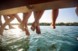 © luckybusiness - Close-up of legs of a group of friends sitting on the dock on the river. Summer, river, vacation