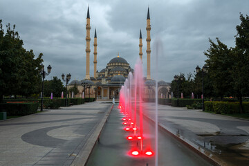 Wall Mural - Alley of red fountains against the background of the Heart of Chechnya mosque on a cloudy September evening. Grozny, Chechen Republic. Russia