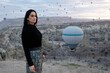 donna mora con maglia nera e gonna a fiori e sullo sfondo le mongolfiere in Cappadocia  in Turchia