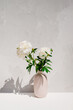 Photo of a beautiful natural gorgeous white peony flowers in a vase outdoor on a harsh sunlight
