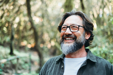 portrait of young mature man alone smiling outside with nature trees in background. environment. hap