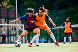 Fototapeta Sport - Female players tackling during soccer practice on playing field.