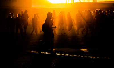 silhouettes of people walking at sunset festival