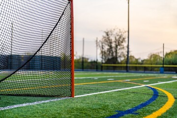 Wall Mural - Late afternoon photo of a lacrosse goal on a synthetic turf field before a night game.
