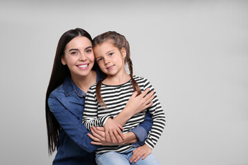 Canvas Print - Happy woman with her cute daughter on light grey background, space for text. Mother's day celebration