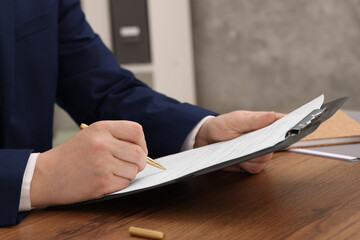 Poster - Man signing document at wooden table, closeup