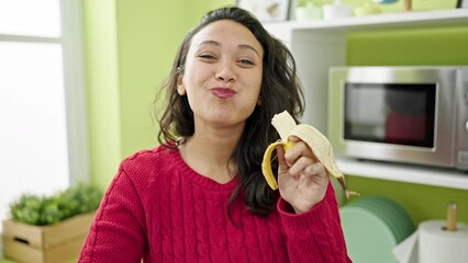 Poster - Young beautiful hispanic woman smiling confident eating banana at dinning room