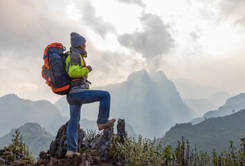 Wall Mural - Hiker standing relaxing on top mountain sunset background. Hiker men's hiking living healthy active lifestyle.