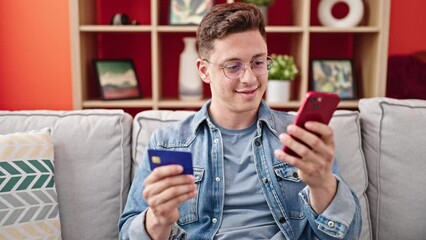 Poster - Young hispanic man shopping with smartphone and credit card sitting on sofa at home