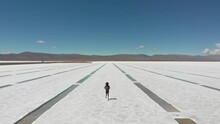 Aerial Of A Lone Figure Runinng Along The Extraction Pits Of The Salt Flats Of Salinas Grandes, Argentina. Drone Dolly Forward