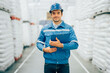 Smart engineer man worker wearing safety helmet doing stocktaking of product management in cardboard box on shelves in warehouse. Factory physical inventory count.
