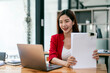 © NAMPIX - businesswoman holding papers preparing report analyzing work results, female executive doing paperwork at workplace using computer for data analysis