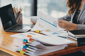 Businesswoman hands working on stacks of paper documents to search and review documents piled on table before sending them to board of directors to use  correct documents in meeting with Businessman