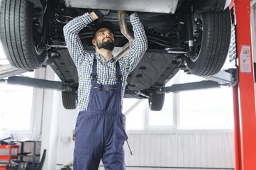 Wall Mural - Auto mechanic working underneath a lifted car