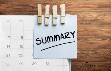 Poster - Blue sticker attached to a calendar on a wooden background with text Summary