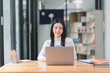 © PRIME STOCK LAB - Portrait of a successful and lovely millennial Asian businesswoman, secretary, sales manager, or business consultant, sitting at her workplace with a laptop, smiling, while dressed casually.