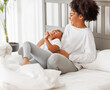 © JenkoAtaman - Happy ethnic family. African american mother and daughter play and laugh in bed.