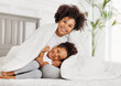 © JenkoAtaman - Happy ethnic family. African american mother and daughter play and laugh in bed.