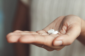 two white pills on asian woman's hand for medical and healthcare concept.