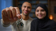 Happy homeowners african american arabian muslim multiracial diversity couple showing keys from new home real estate house looking at camera relocation day bank loan mortgage for young family concept