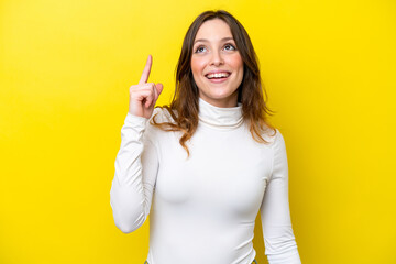 Canvas Print - Young caucasian woman isolated on yellow background pointing up and surprised