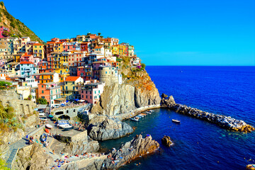 Wall Mural - Colorful Cinque Terre village of Manarola, Italy. View of the harbor with boats in the blue sea.