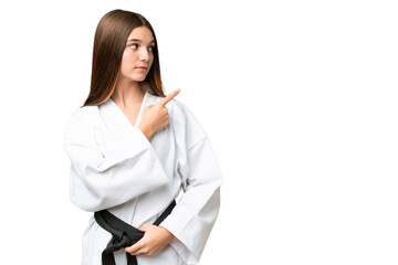 Sticker - Teenager girl over isolated chroma key background doing karate and pointing to the lateral