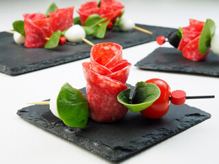 Wall Mural - Close-up of canape with salami and mozzarella in the form of a rose flower with leaves