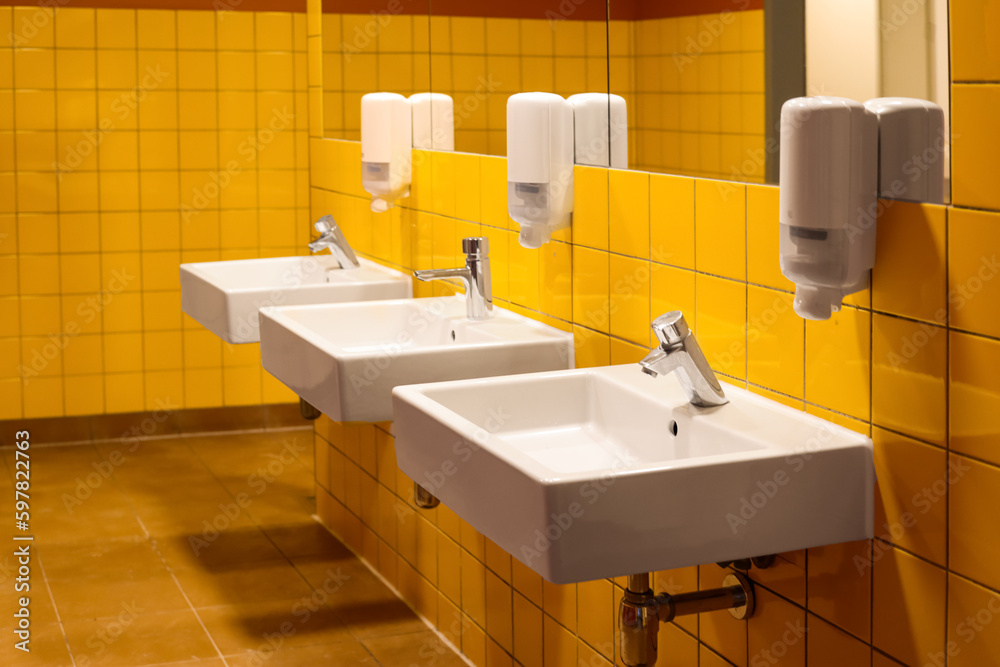 View of sinks with automatic soap dispensers in public restroom