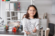 © Pixel-Shot - Little girl with safety goggles and molecular model in science classroom