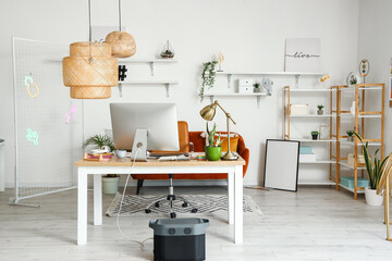 Interior of office with graphic designer's workplace, shelves and sofa