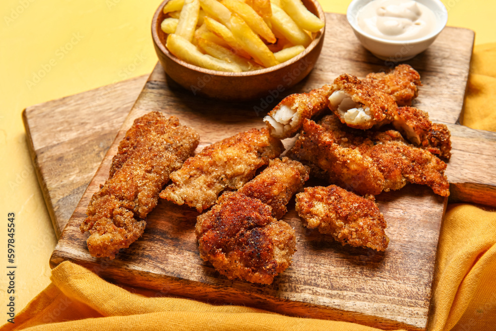Wooden boards of tasty fried codfish on yellow background