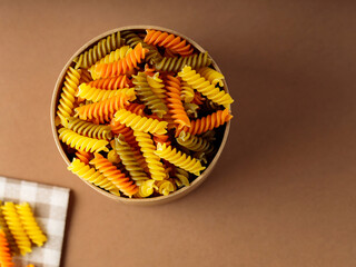 Wall Mural - Three colors fusilli pasta on a linen napkin. Green, orange and yellow fusilli pasta stored in eco box. Copy space