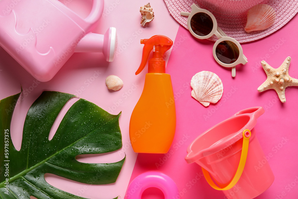 Sunscreen cream for baby with beach accessories, seashells and palm leaf on pink background