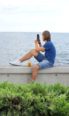 Wall Mural - young man walking along the promenade and taking pictures