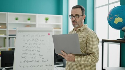 Sticker - Middle age man teacher teaching lesson using laptop at classroom