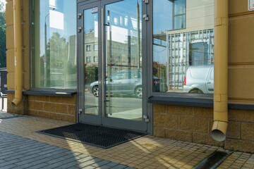 Large glass doors at the entrance to the mall. Empty shop windows without signage and brand names. Lack of advertising in modern stores.